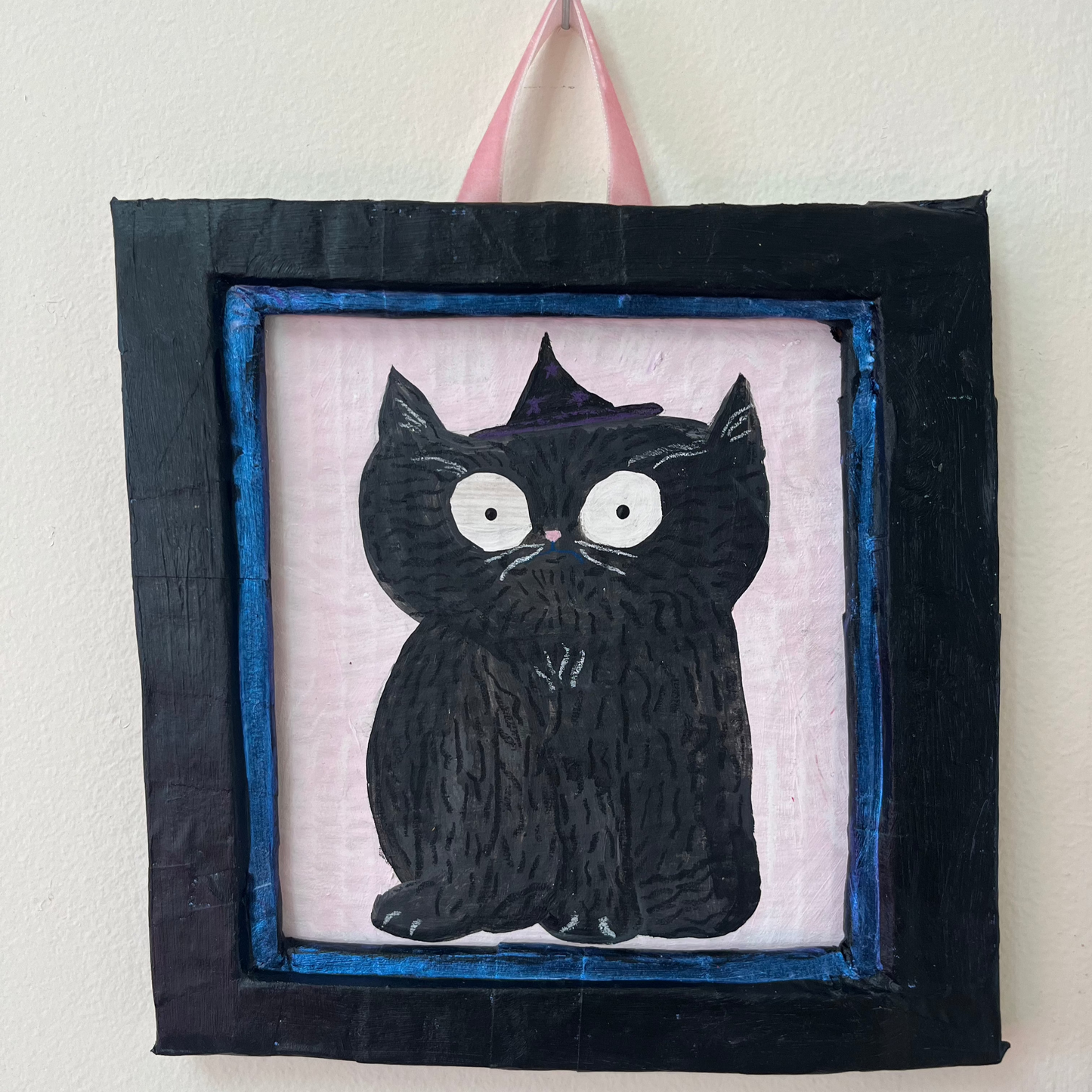 black cat with black and purple witch hat on pink background painting in black frame all made out of recycled paper.